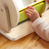 A toddler is interacting with a wooden spinning drum toy designed for Montessori play.