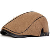 A brown knit newsboy cap with a black trim and adjustable side buckle shown from the side.