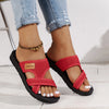 A pair of red breathable mesh flat sandals with black soles and gold bead accents worn on a person's foot.