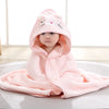 A baby wearing a pink animal hooded bath towel with a hood, lying on a white surface.