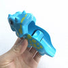 A hand holds a bright blue marble run building block piece with yellow dots.