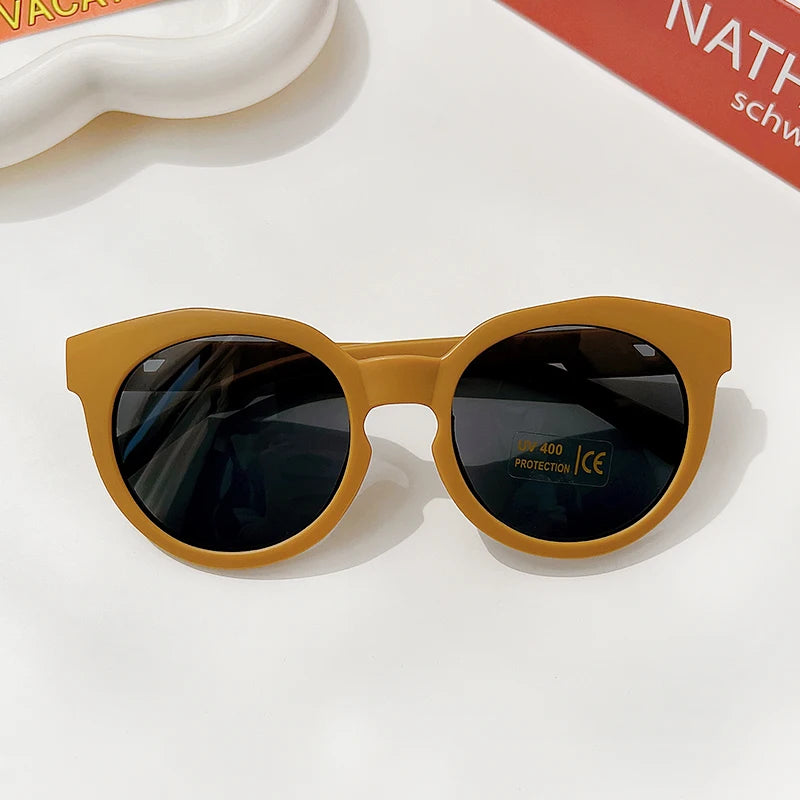 A pair of yellow sunglasses with dark lenses and a durable frame resting on a white surface.