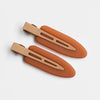 A set of two matte resin side hair clips in a warm terracotta color, shown against a white background.