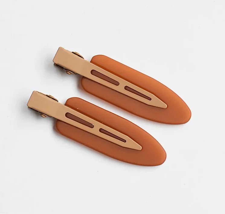 A set of two matte resin side hair clips in a warm terracotta color, shown against a white background.