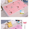 Pink waterproof baby mattress protector with cute cartoon designs on a light-colored surface.