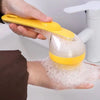 A hand is using a yellow pet bath brush with a silicone dispenser to apply shampoo foam onto a pet's fur.