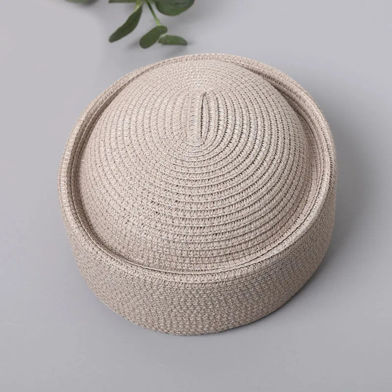 A beige straw pillbox sun hat with a wide brim shown from above.