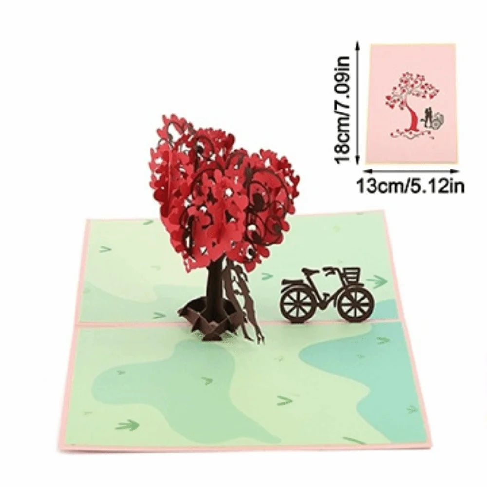 A pink card featuring a red tree silhouette and a bicycle silhouette on a light green background.