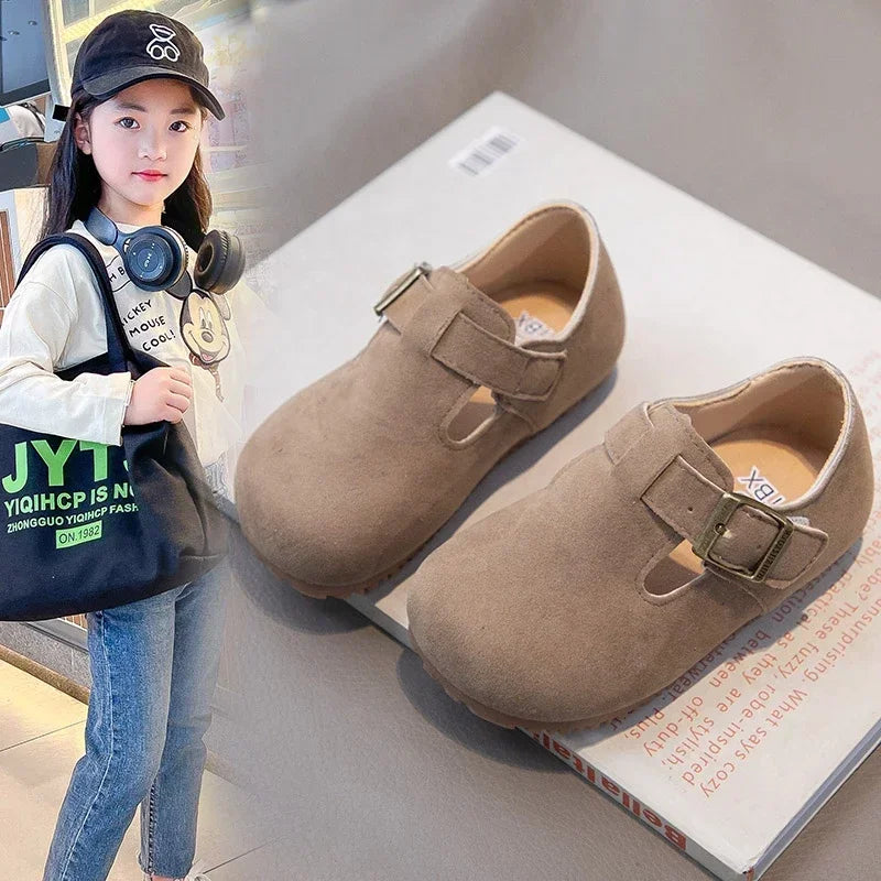 A young girl models retro non-slip moccasin shoes with hook-and-loop closure.
