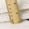A wooden ruler measuring 9 centimeters placed on a white, fluffy fleece fabric.