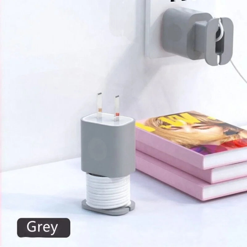 A grey silicone charger protector and cable organizer with two charging tips is shown on a white surface.