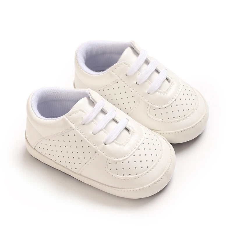 A pair of light beige baby pre-walker sneakers with white laces and a light gray lining.
