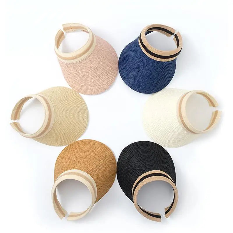 A collection of five woven straw sun hats in various shades of beige, tan, and navy blue arranged in a circle.
