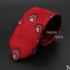 Corbata jacquard roja con patrón circular repetido, doblada sobre fondo oscuro.