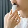 Persona usando un dispositivo compacto blanco recargable para recortar vello de nariz y orejas.
