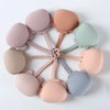 A circular arrangement of ten silicone pacifier storage cases in various pastel colors, including pink, peach, mint green, an