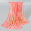 A flowing peach colored chiffon scarf with gold shimmer detailing, displayed on a hanger.