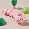 A pink wind-up crawling animal toy with large eyes and pink body is shown next to green toys.