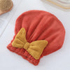 Gorro de microfibra color terracota con moño amarillo oro sobre superficie blanca
