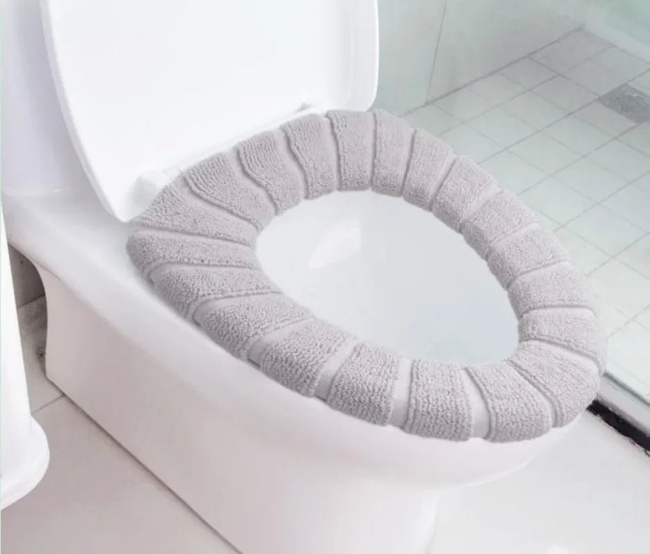 A light gray, textured acrylic toilet seat cover is placed on a white toilet bowl.