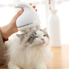Un gato blanco y esponjoso recibe un masaje en la cabeza con un dispositivo eléctrico blanco.