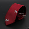 Corbata roja con estampado de caballo plateado sobre fondo oscuro.