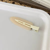 A pair of matte resin side hair clips resting on a white tray.