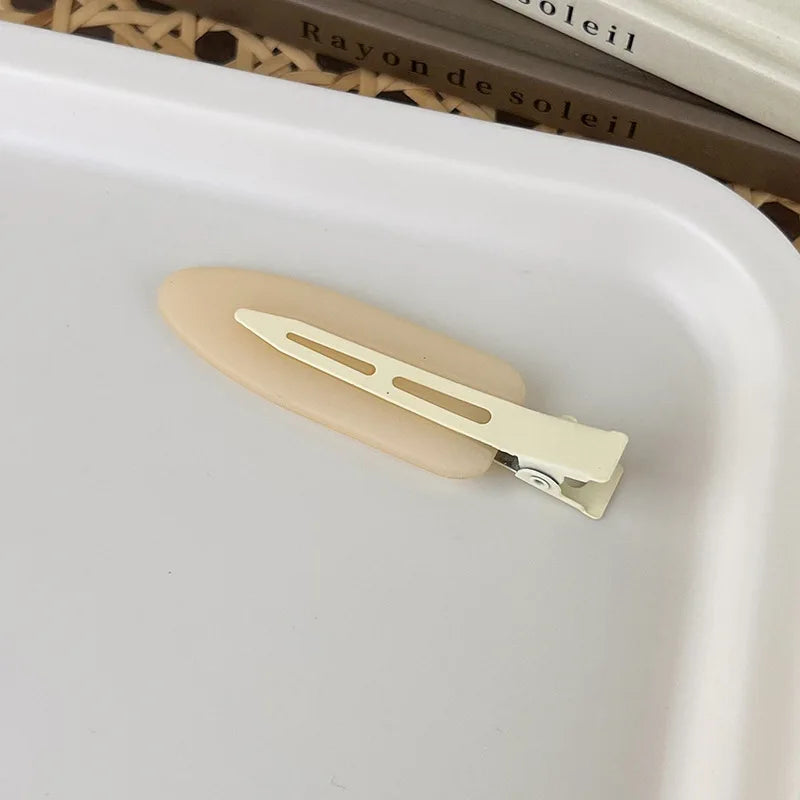 A pair of matte resin side hair clips resting on a white tray.