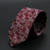 Corbata granate con diseño floral blanco, enrollada sobre fondo oscuro.