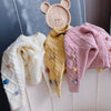 A display of knitted sweaters and a wooden animal decoration featuring pom-pom trim.