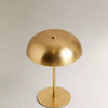 A brass-colored portable touch table lamp with a dome shade mounted on a circular base.