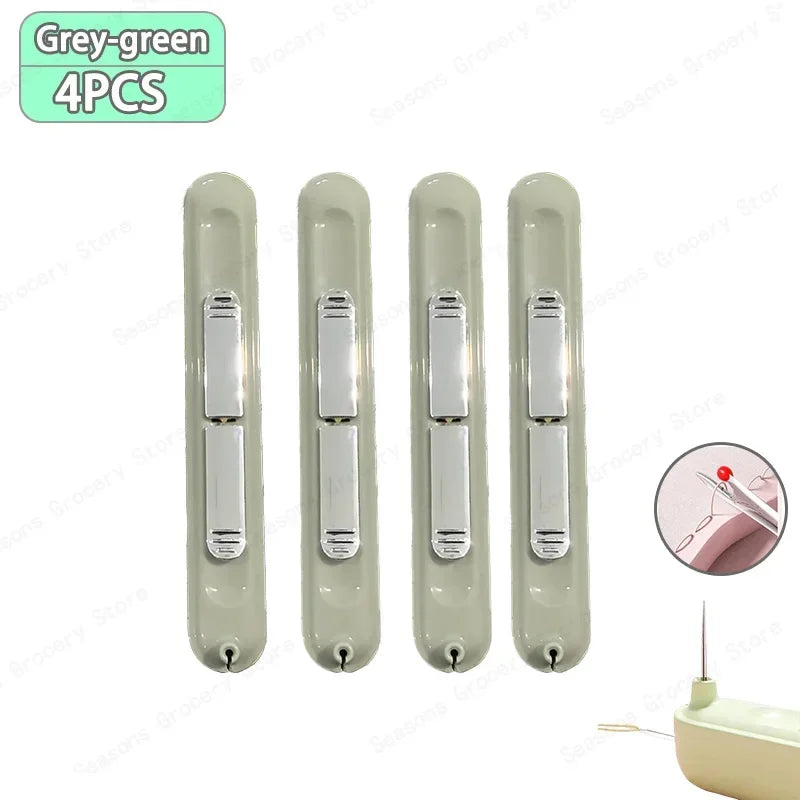 A set of four grey-green needle threaders and seam rippers for sewing projects.