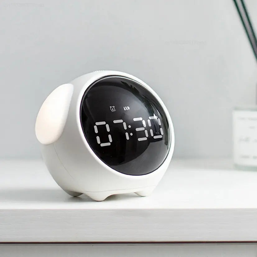 A white, spherical alarm clock with a black display showing 07:30 sits on a white surface.