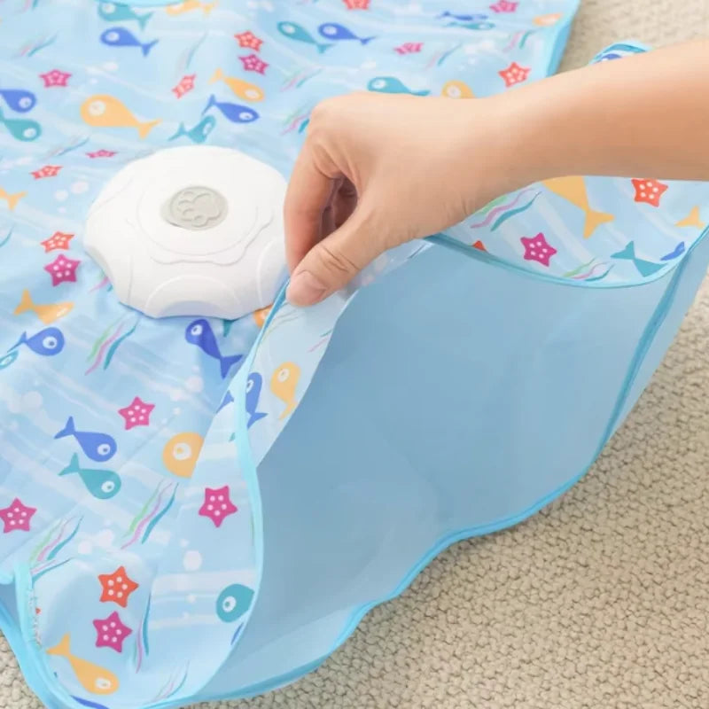 A hand is placing a white motion-activated hide and seek cat toy onto a light blue patterned fabric.