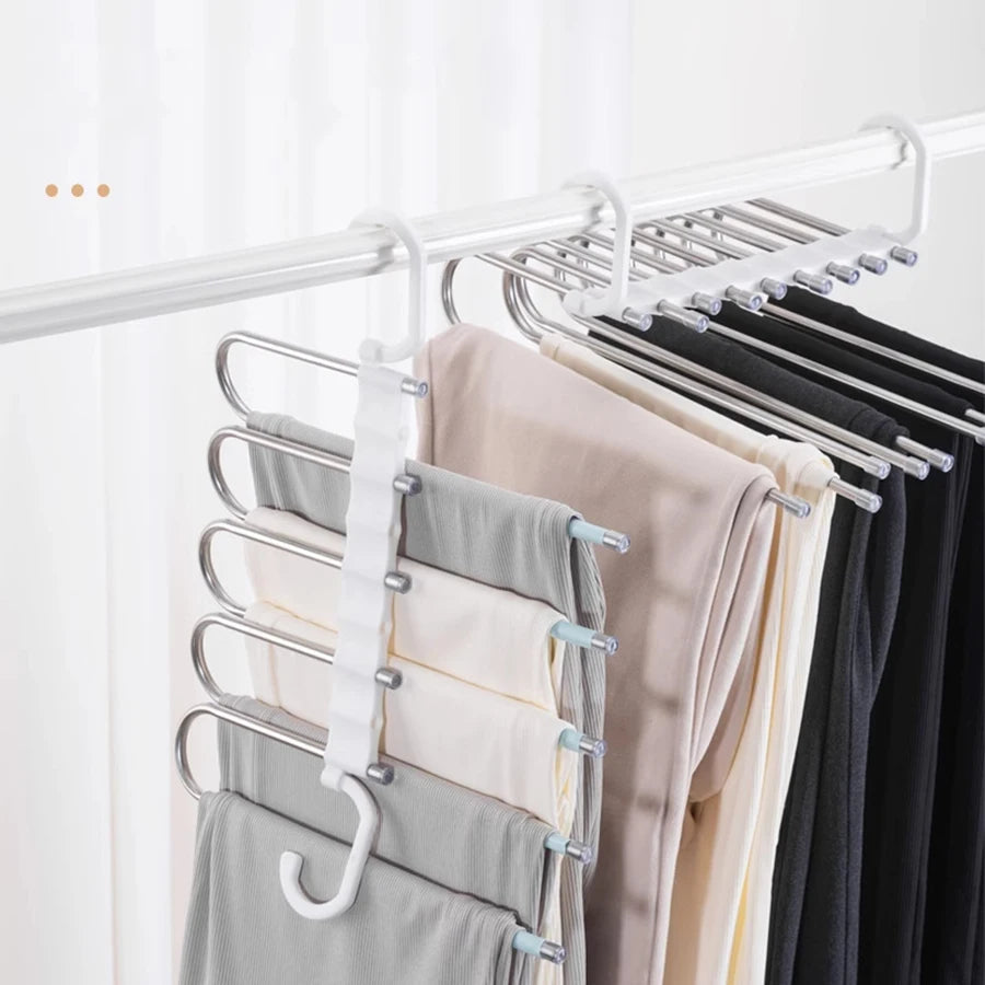 Estante plegable blanco con perchas mostrando varios pantalones de colores.