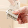 A hand is holding a white retractable ceramic blade cutter with a magnetic lock mechanism.