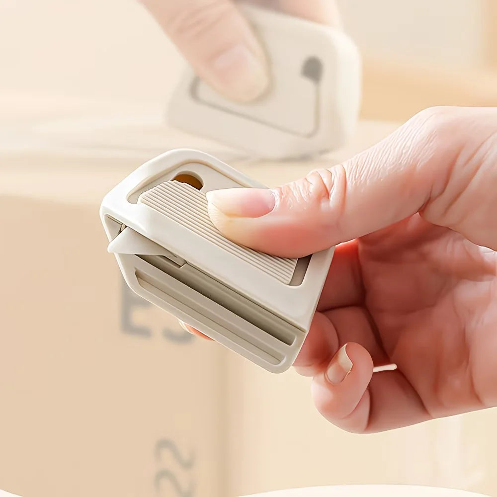 A hand is holding a white retractable ceramic blade cutter with a magnetic lock mechanism.