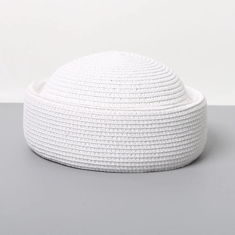 A white straw pillbox sun hat with a wide brim shown against a gray background.