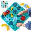 A child is assembling a colorful logical road building maze on a green board with various colored plastic pieces.