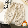 Light beige fleece-lined pants with a small floral print shown flat lay next to a white cap and shoes.