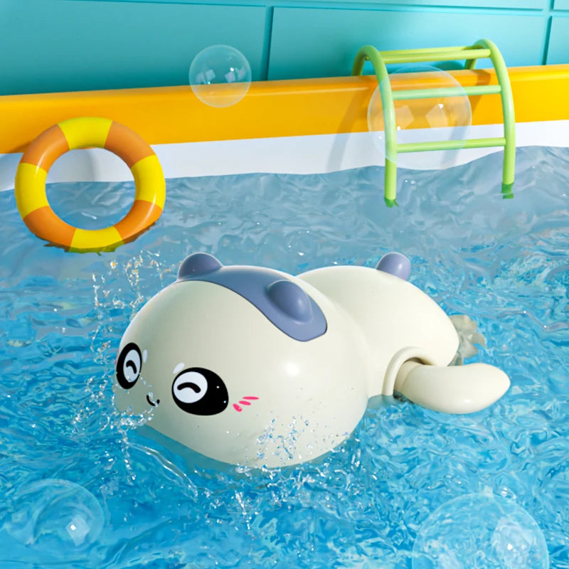 A white and gray cute duck and penguin bath toy floating in blue water with a yellow ring and green rack visible.