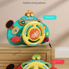 A bright teal interactive steering wheel toy with a yellow wheel and lights, shown on a wooden surface.
