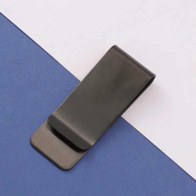 A black metal tie clip lying on a blue-gray surface.
