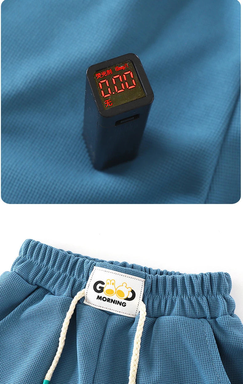 A small black electronic device is placed on a blue fabric, next to a pair of blue kids' beach shorts.