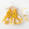 A yellow floral dress for a baby girl with a matching straw sunhat displayed on a wooden hanger.