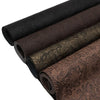Rolls of vintage floral textured faux leather fabric in various shades of brown and black.