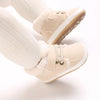 A pair of beige soft cotton baby winter snow boots with fuzzy trim and white socks.