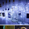 A row of glass bottles illuminated by LED fairy lights, creating a decorative display.