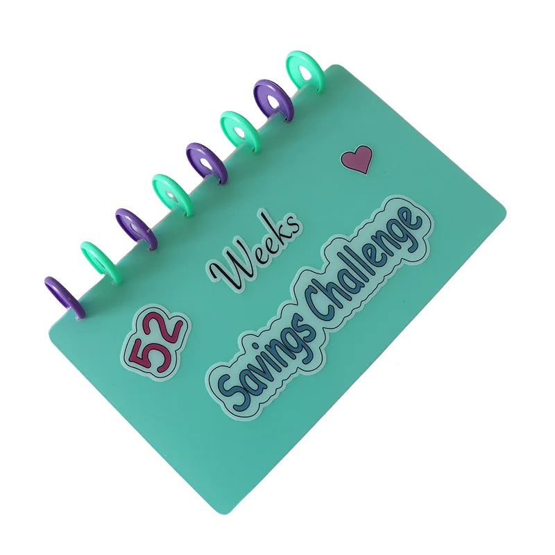 A green binder with 52 purple and green pins, labeled Savings Challenge Weeks.