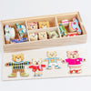 A wooden puzzle set featuring various bear figures in different outfits and colors, displayed in a light wood box.
